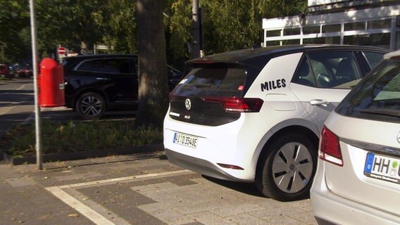 Ein weißes Auto mit der Aufschrift "miles" steht auf einem Parkplatz. © Screenshot 