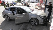 Polizistinnen und Polizisten stehen an einem grauen Auto mit Frontschaden. © Screenshot 