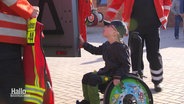 Ein kleiner Junge im Rollstuhl schaut gespannt in ein Feuerwehrauto. © Screenshot 