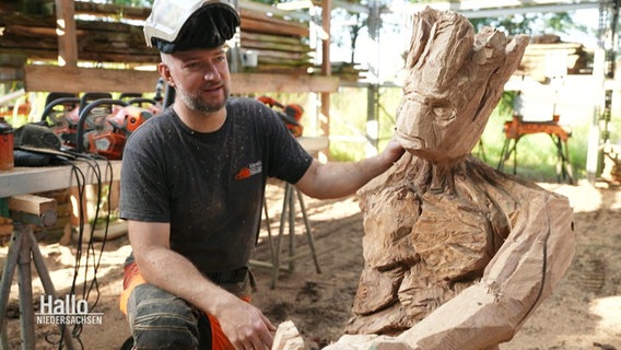 Steffen Merla mit einer von ihm geschnitzten Holzfigur. © Screenshot 