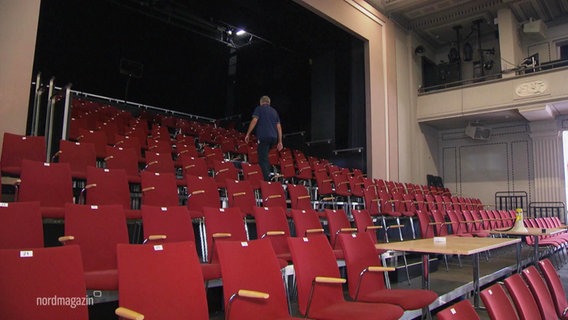Reihen von roten Stühle stehen in einem großen Saal. © Screenshot 
