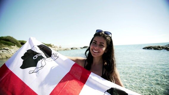 Serena Loddo auf Sardinien mit einer sardischen Fahne © Screenshot 