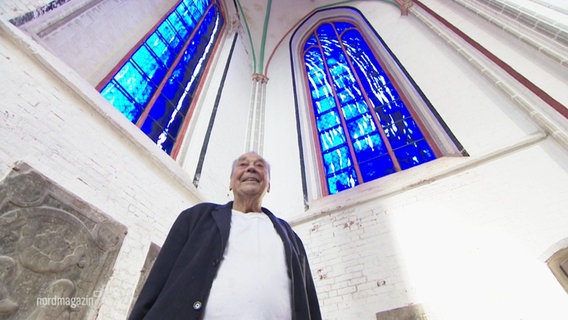 Günther Uecker vor den von ihm entworfenen, strahlend blauen Kirchenfenstern. © Screenshot 