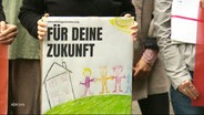 Eine Person hält ein Schild mit der Aufschrift "Für deine Zukunft" in den Händen. © Screenshot 
