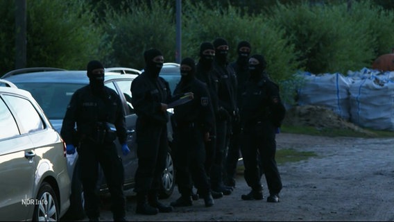 In schwarz gekleidete Polizeibeamte vor einer Razzia. © Screenshot 