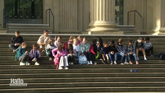 Eine Grundschulklasse sitzt auf den Stufen des Landtages. © Screenshot 