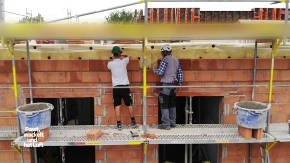 Menschen auf einem Baugerüst an einer Hausfassade. © Screenshot 