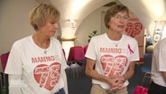 Zwei Personen mit T-Shirts auf denen steht: Mammobis, 75. © Screenshot 