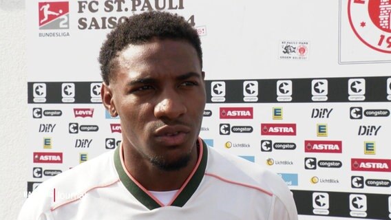 Oladapa Afolayan, SPieler beim FC St. Pauli, vor einer Sponsorenwand im Interview © Screenshot 
