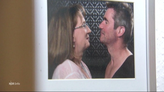 Ein Mann und eine Frau schauen sich auf einem eingerahmten Bild verliebt in die Augen. © Screenshot 