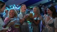 Frauen in Dirndln trinken in einem Festzelt aus großen Bierkrügen. © Screenshot 