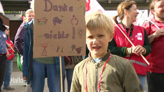 Ein kleiner Junge hält ein Schilöd mit der Aufschrift: "Danke für nichts!". © Screenshot 