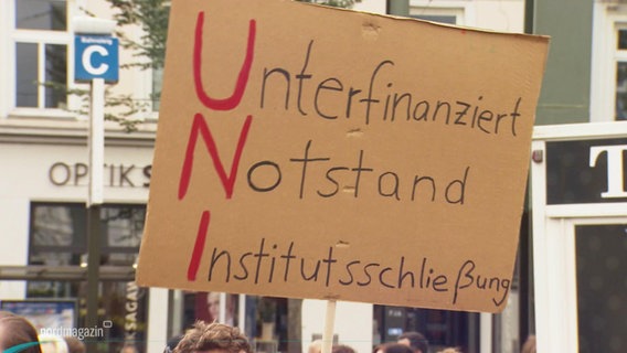 Ein Schild auf einer Demo trägt die Aufschrift: "Unterfinanziert, Notstand, Institutionsschließung". © Screenshot 