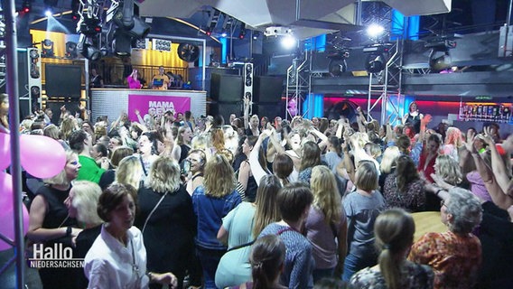 Viele Frauen stehen in einer Disco auf der Tanzfläche und feiern. © Screenshot 