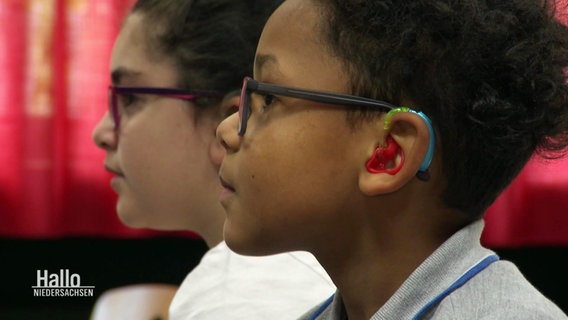 Ein Junge trägt ein buntes Gerät in seinem Ohr. © Screenshot 