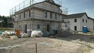 Ein Haus das gerade neu gebaut wird ist von Gerüsten umgeben. © Screenshot 