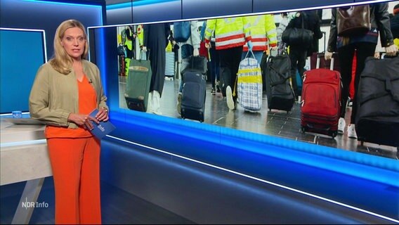 Nachrichtensprecherin Juliane Möcklinghoff, im Hintergrund ein Bild von Menschen mit Koffern. © Screenshot 
