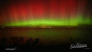 An einem dunklen Himmel sind strahlende rote und grüne Lichter zu sehen. © Screenshot 