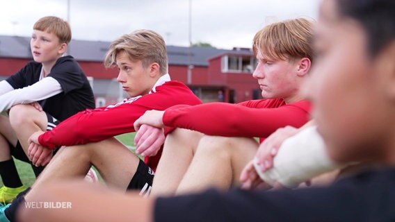 Junge Fussballspieler sitzen auf dem Spielfeld. © Screenshot 