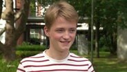 Ein lächelnder blonder junger Mann mit geringeltem Shirt © Screenshot 