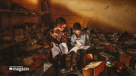 Das Foto zweier Kinder, die in einer zerstörten Bibliothek sitzen und lesen. © Screenshot 