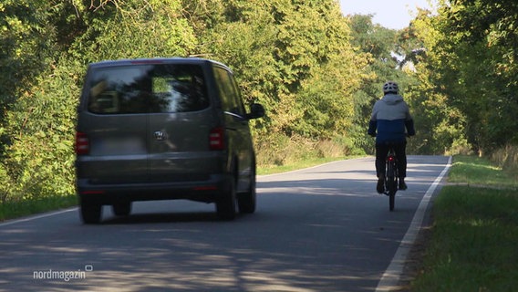 Ein PKW-Bus überholt auf einer Landstraße einen Fahrradfahrer. © Screenshot 