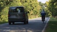 Ein PKW-Bus überholt auf einer Landstraße einen Fahrradfahrer. © Screenshot 