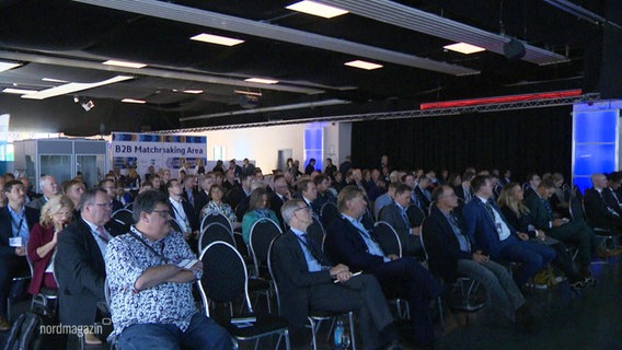 Auf einem Kongress sitzen viele Menschen in Stuhlreihen in einem Publikum. © Screenshot 