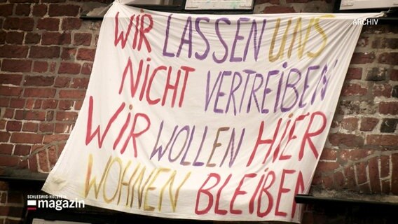 Archiv: auf einem alten Banner steht: Wir lassen uns nicht vertreiben. Wir wollen hier wohnen bleiben. © Screenshot 