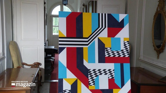 Buntes Gemälde steht auf einem Stuhl. © Screenshot 