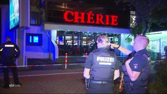 Polizisten stehen vor einer Bar. © Screenshot 