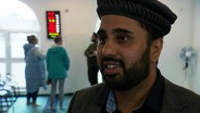 Danial Wadood, Gemeindemitarbeiter, im Interview. Er ist ein Mann mit kurzem Vollbart und einem Hut auf dem Kopf. © Screenshot 