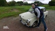 Zwei Menschen die ein Auto wischen, das an einer Brücke steht. © Screenshot 