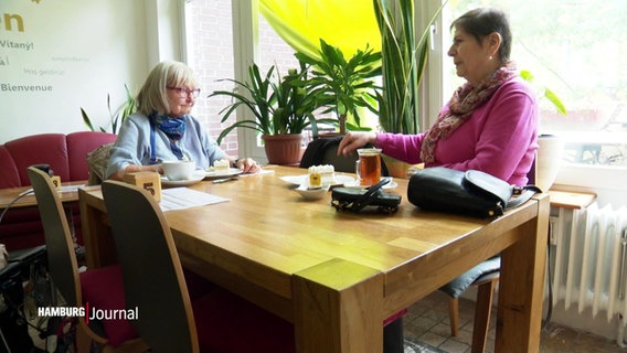 Zwei Frauen sitzen an einem Tisch. © Screenshot 