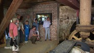 Besuchende im inneren einer historischen Wassermühle in Hanshagen. Im Mittelalterlichen Bau arbeiten Wasserrad und Zahnränder. © Screenshot 
