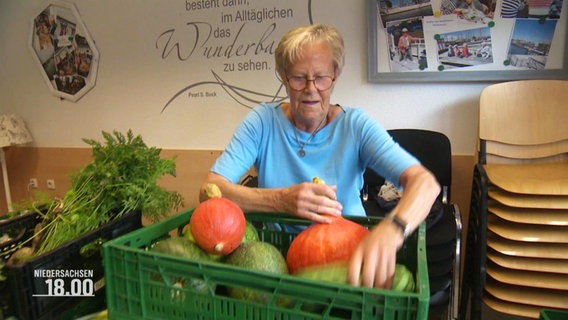 Eine Frau packt eine Kiste mit Kürbissen und Zucchini. © Screenshot 