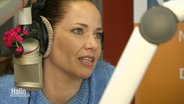 Die Schauspielerin Katja Frenzel spricht in einem Tonstudio in ein Mikrophon. © Screenshot 