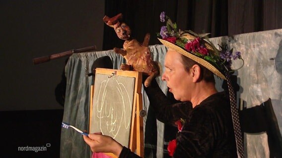 Eine Schauspielerin spricht auf der Bühne mit einem Hasen als Handpuppe. © Screenshot 