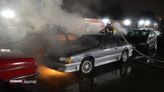 Ein brennendes Auto wird von der Feuerwehr gelöscht. © Screenshot 