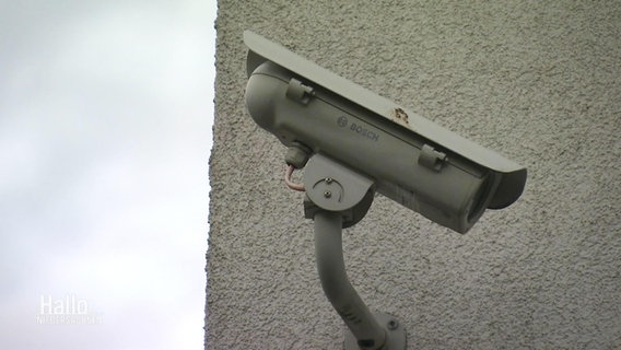 Eine Überwachungskamera an einer grau verputzten Außenwand. © Screenshot 