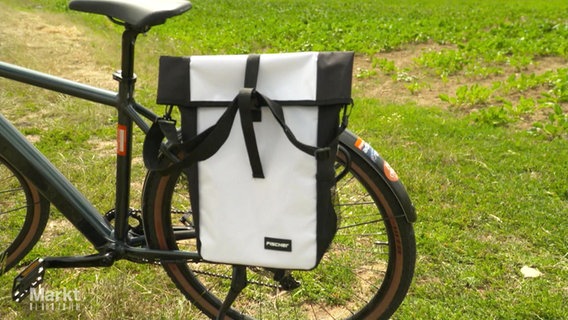 Eine schwarz-weiße Fahrradtasche an einem Rad. © Screenshot 