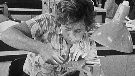 Schwarz-Weiß-Bild von 1978 zeigt eine Frau bei Metall-Arbeiten an einer Platte. © Screenshot 