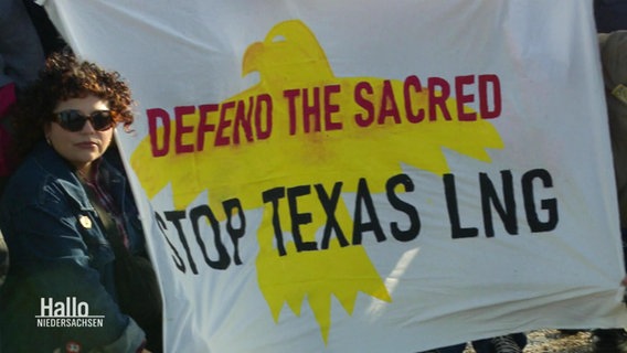 Mehrere Personen halten ein Banner mikt der Aufschrift: "Defend the Sacred Stop Texas LNG". © Screenshot 
