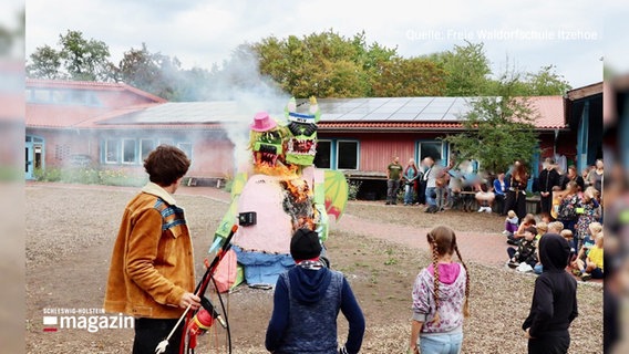Menschen die mit einem Brenngerät eine Skulptur auf einem Hof anzünden. © Screenshot 