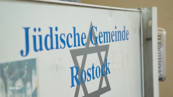 Ein weißes Schild mit grauem Davidsstern. Darüber steht in blauer Schrift geschrieben: Jüdische Gemeinde Rostock. © Screenshot 