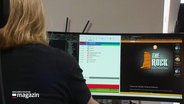 Von hinten zu sehen sitz ein Mann an einem Schreibtisch vor zwei Computer-Bildschirmen. © Screenshot 
