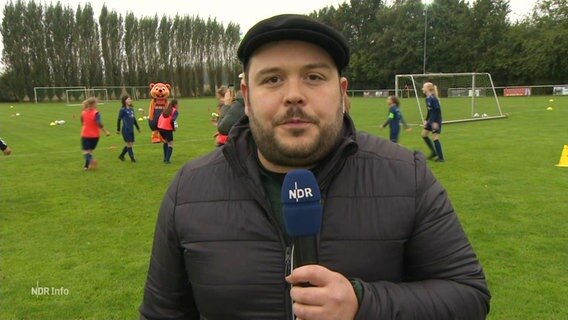 NDR-Reporter Jan Bockemüller steht am Rand eines Fußballfeldes. © Screenshot 