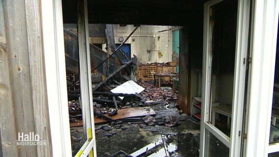 Blick durch eine Tür auf die Überreste eines vom Feuer zerstörten Raumes. © Screenshot 