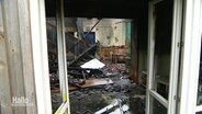Blick durch eine Tür auf die Überreste eines vom Feuer zerstörten Raumes. © Screenshot 