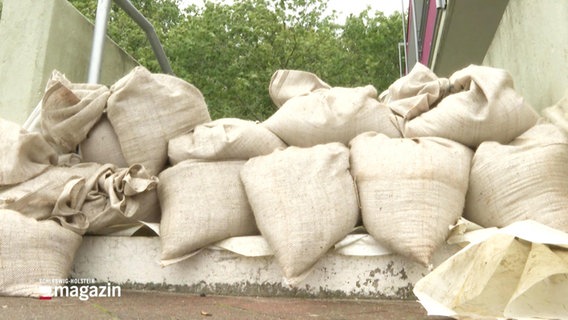 Mehrere Sandsäcke sind in einen Hauseingang gestapelt. © Screenshot 